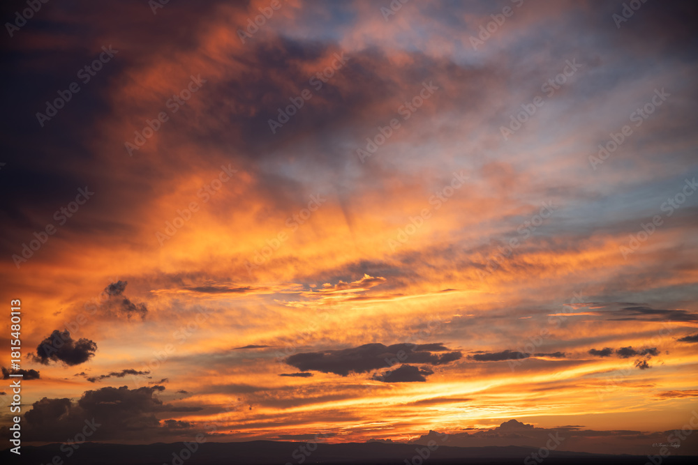 Obraz premium Expansive Wyoming sky with dramatic golden and orange clouds at sunset