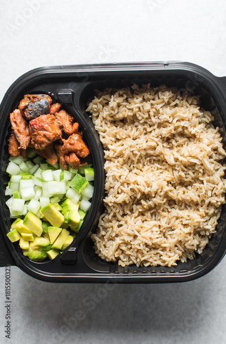 Overhead view of  a healthy rice bowl in a plastic plate, top view of rice, diced cucumber avocado amd fish in a bowl, yop view of a healthy rice bowl