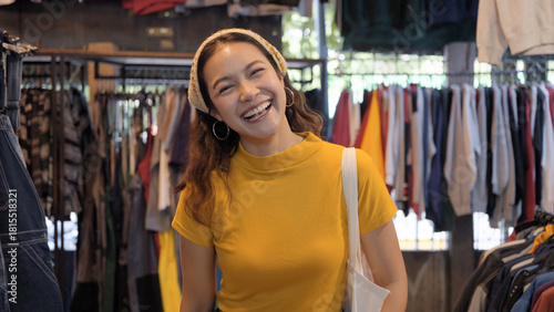 Young teen Gen Z asia female happy smile looking at camera at zero waste eco go green buy second hand sale store flea market mall thrift old used vintage fabric retro style. Woman people enjoy shop.