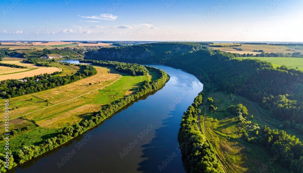 Fototapeta premium Expansive River Winding Through Lush Green Countryside Under a Clear Blue Sky with Soft Sunlight