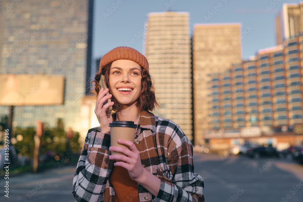 Fototapeta premium woman coffee phone smile urban beanie candid lifestyle portrait in golden hour glow, authenticity and mindful living captured with emotional storytelling in contemporary city street.