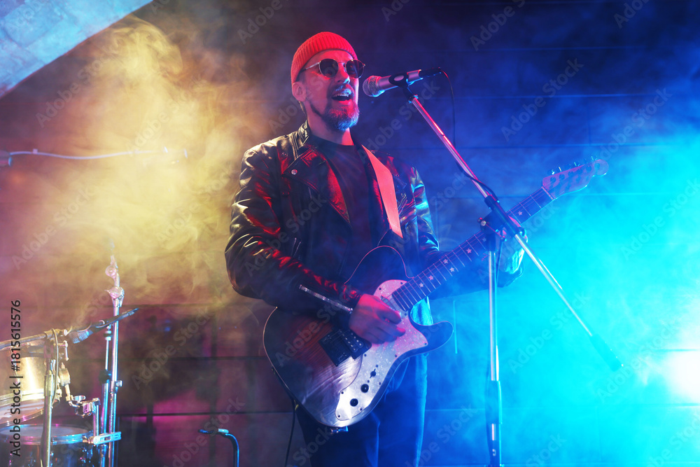Obraz premium Man playing electric guitar on stage with smoke