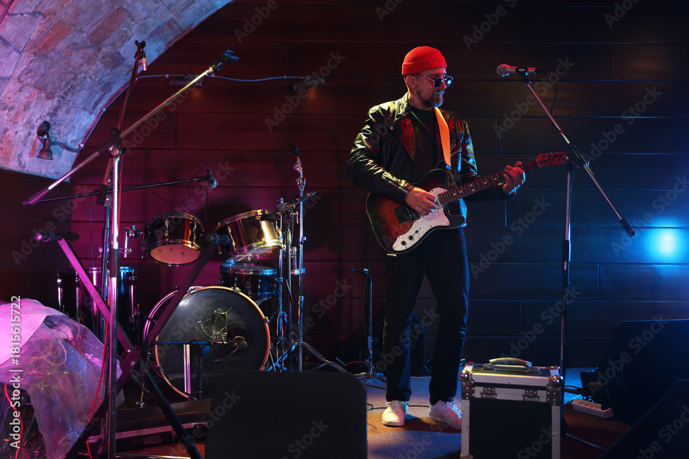 Obraz premium Handsome man playing electric guitar on stage
