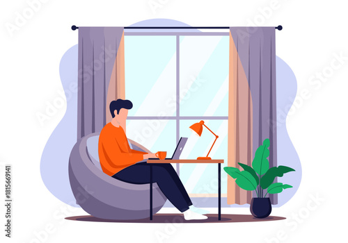 A young man working or studying from home on his laptop while sitting comfortably in a beanbag chair by the window.