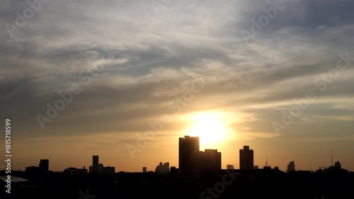 Time-lapse of Golden light pours across the horizon, highlighting the silhouettes of tall buildings