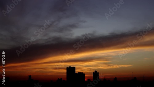 Time-lapse of Vibrant colors spread across the sky as the evening deepens over the urban skyline.