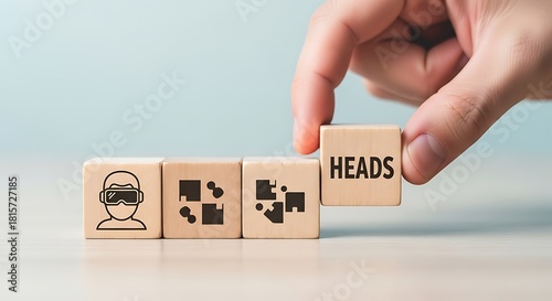 Hand placing wooden block with word heads next to block with virtual reality headset icon representing digital future