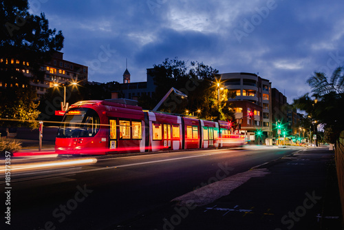 Long exposure red light rail train waiting at Newcastle Beach stop tram station at night 