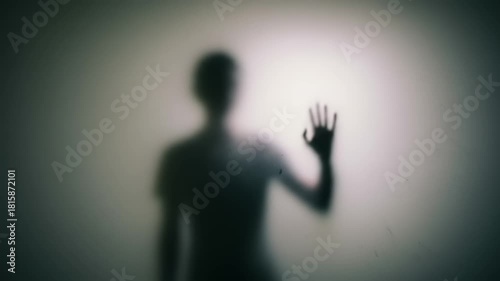 Silhouette of a person reaching out with a hand against a softly lit wall, evoking feelings of isolation