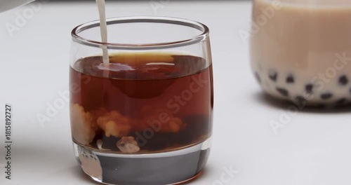 Dark Tea in Glass Cup with Milk Tea Beverage Background - Traditional Drink Preparation and Pouring Concept