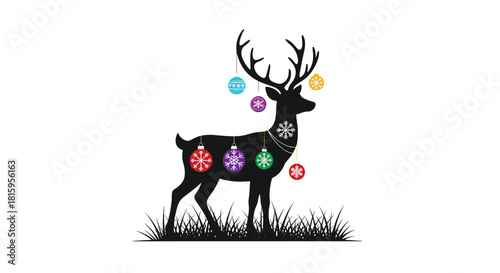 A black silhouette of a majestic deer decorated with colorful hanging Christmas ball ornaments standing in grass on white background.