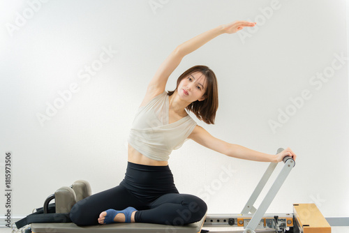 Fototapeta ピラティス女子 日本人女性がリフォーマーでポーズ