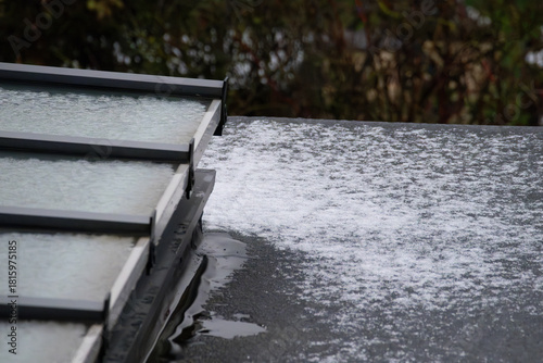 Close-up of flat roof and glass skylight covered in melting snow and ice in winter