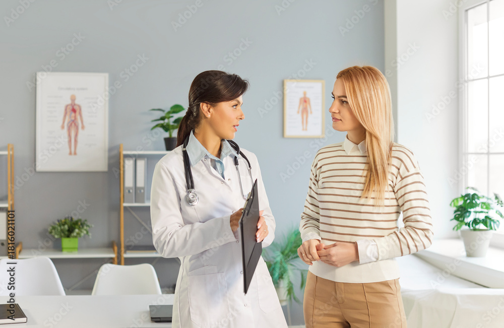 Obraz premium Young doctor woman holding report file with appointment and prescribe treatment to a female sick patient standing in clinic during medical examination. Medicine and health care concept.