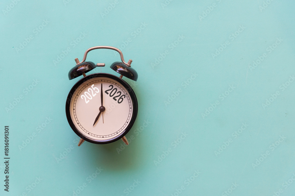 Naklejka premium 2025 and 2026 on black alarm clock on blue background, Merry Christmas and Happy new year concept. Copy space and banner for text