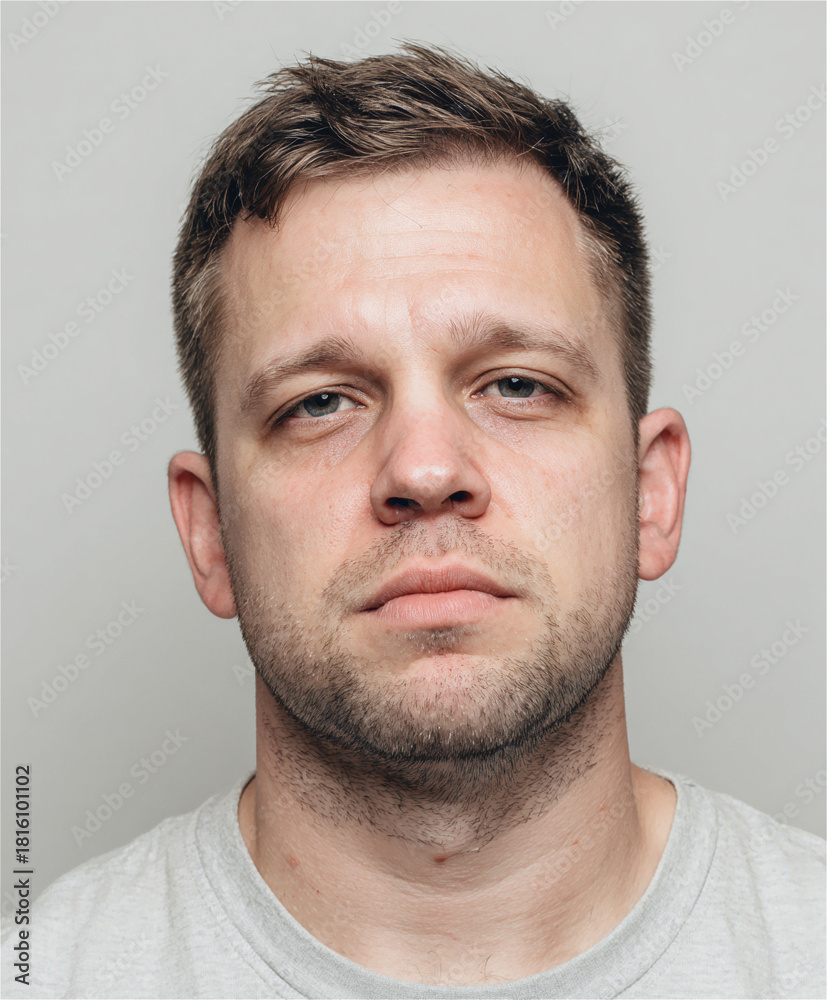 Obraz premium Headshot authentic man light stubble messy hair tired sad serious expression portrait real person casual wear simple studio background