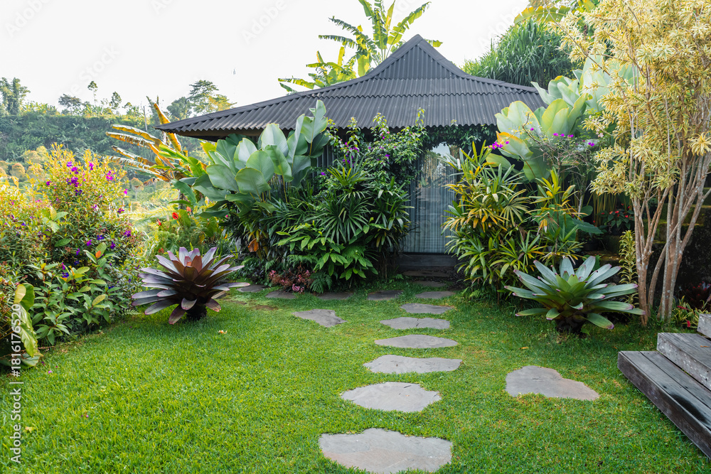 Fototapeta premium Tropical villa surrounded by lush greenery and vibrant exotic plants.