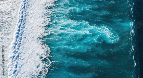 Fototapeta Naklejka Na Ścianę i Meble -  Stunning aerial top-down view of a powerful ocean wave breaking, with white sea foam creating abstract patterns on the deep turquoise water surface, a beautiful natural background