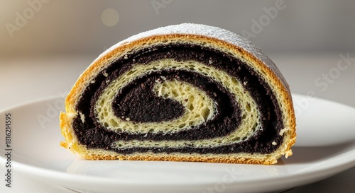 Close-up of a delicious slice of poppy seed roll dusted with powdered sugar on a white plate.