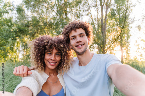 Obraz na plátně Happy young couple with curly hair smiling and looking at the camera, taking a s