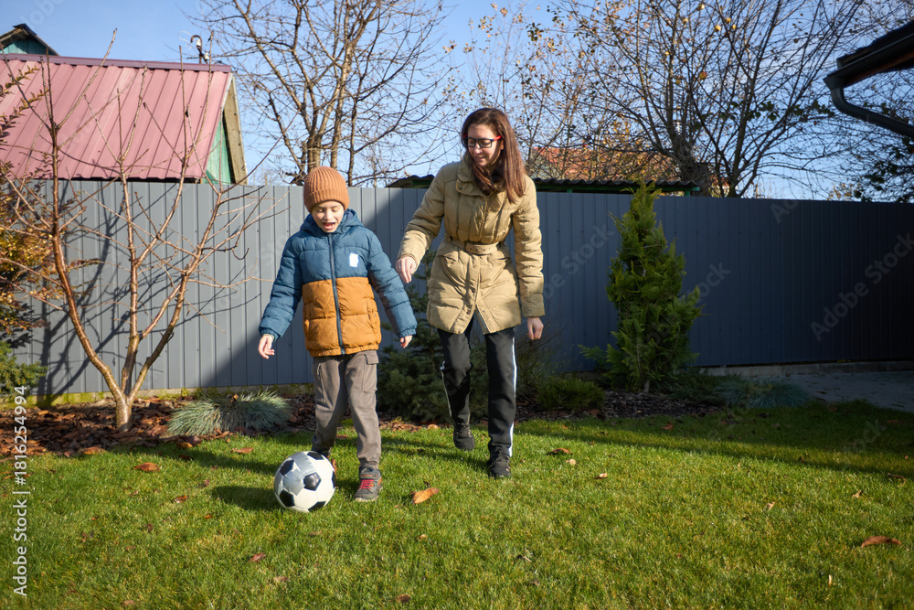 Naklejka premium Mother and son enjoy a soccer game in autumn backyard scene