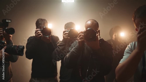 Group of paparazzi photographers taking pictures with camera flash in dark setting
