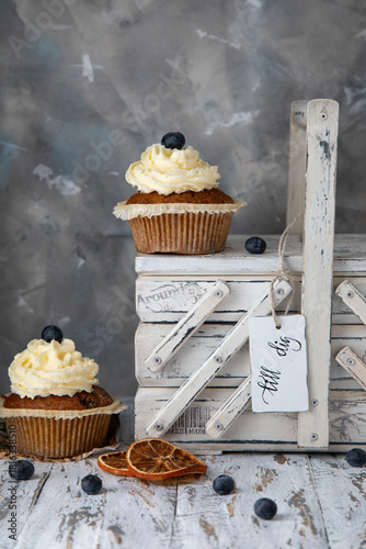 Homemade cupcakes with buttercream frosting and a white vintage box with a name tag that reads 