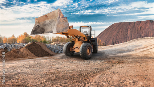 Foto A large wheel loader removes soil from a site surrounded by hills