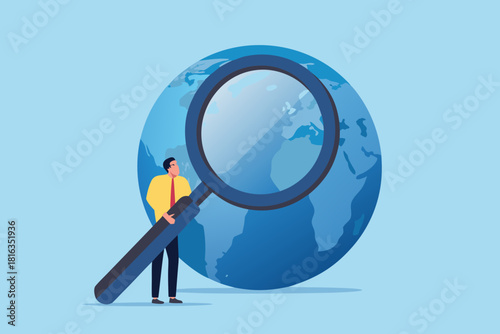 Businessman holding a magnifying glass in front of a globe illustration