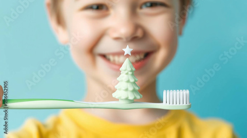Portrait of a smiling child, holding a green toothbrush horizontally, toothpaste shaped as a Christmas tree.