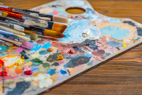 Old used brushes in an artist's studio, palette with multi-colored spots of oil or acrylic paint