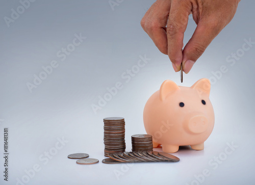 money saving concept. business man han dropped coin on piggy bank with coin stack on dark blue background. money matters tips to investment and business financial banking for Financial Wellness.