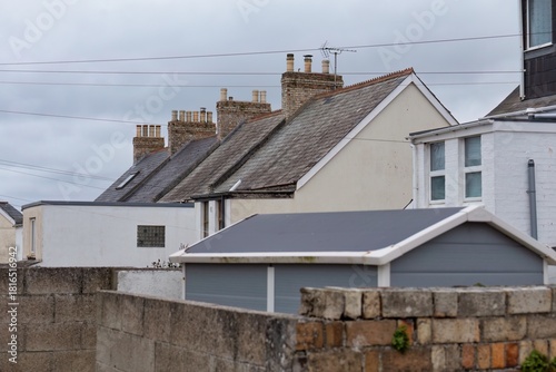 A row of houses features gabled roofs and chimneys under a cloudy sky in Newquay - Cornwall - UK