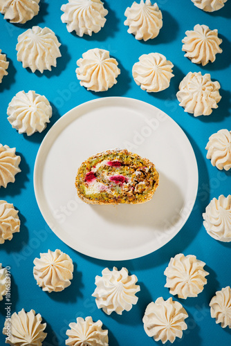 Sweet meringue pistachio roll with raspberry on Blue background