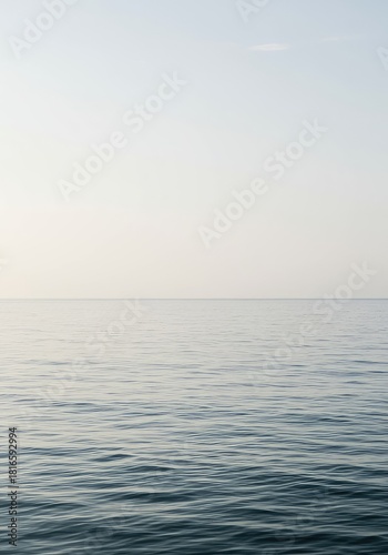 Expansive view of an empty ocean surface meeting a cloudless, pale sky, creating a minimalist, neutral backdrop for design or conceptual projects ,empty ,mood ,horizon