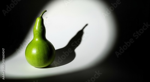 A Green Gourd Illuminated, Casting A Dramatic Shadow Against A Stark White Backdrop