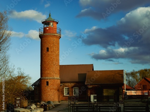Fototapeta Naklejka Na Ścianę i Meble -  An old red lighthouse on the shore of the Baltic Sea in sunny weather