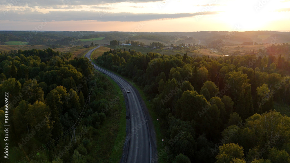 Fototapeta premium a highway in the mountains at sunset with a car driving along it