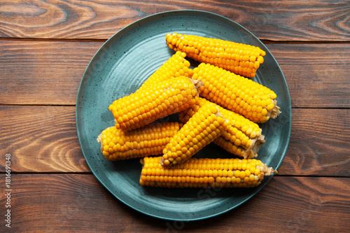 boiled corn in a gray plate on a wooden table. yellow corn in the kitchen on the table
