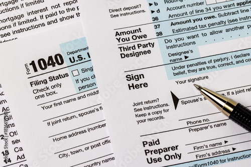 Signing 1040 federal income tax form. Tax preparation, fraud, and filing taxes concept.