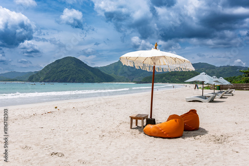 Lombok Indonesia – White sand and shaded loungers overlooking the wide panoramic shoreline of Selong Belanak Beach.