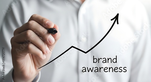 A person drawing an upward trending arrow with the words brand awareness isolated on white background