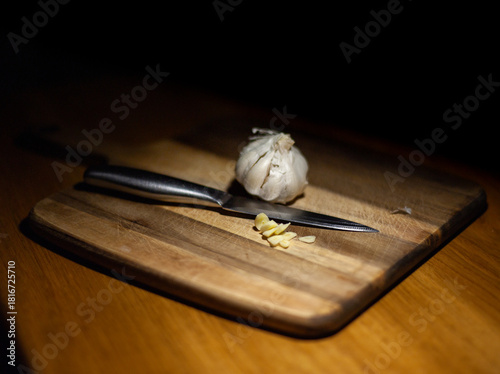Close-up of a bulb of garlic on a wooden chopping board with a sliced clove of garlic