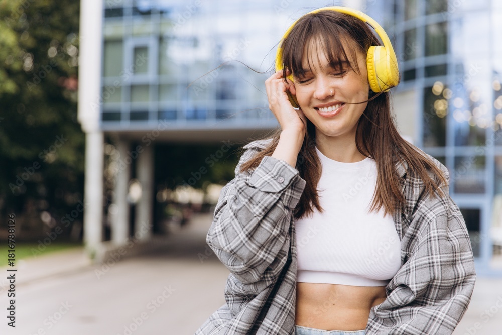 Fototapeta premium Young woman enjoying music with headphones in urban environment