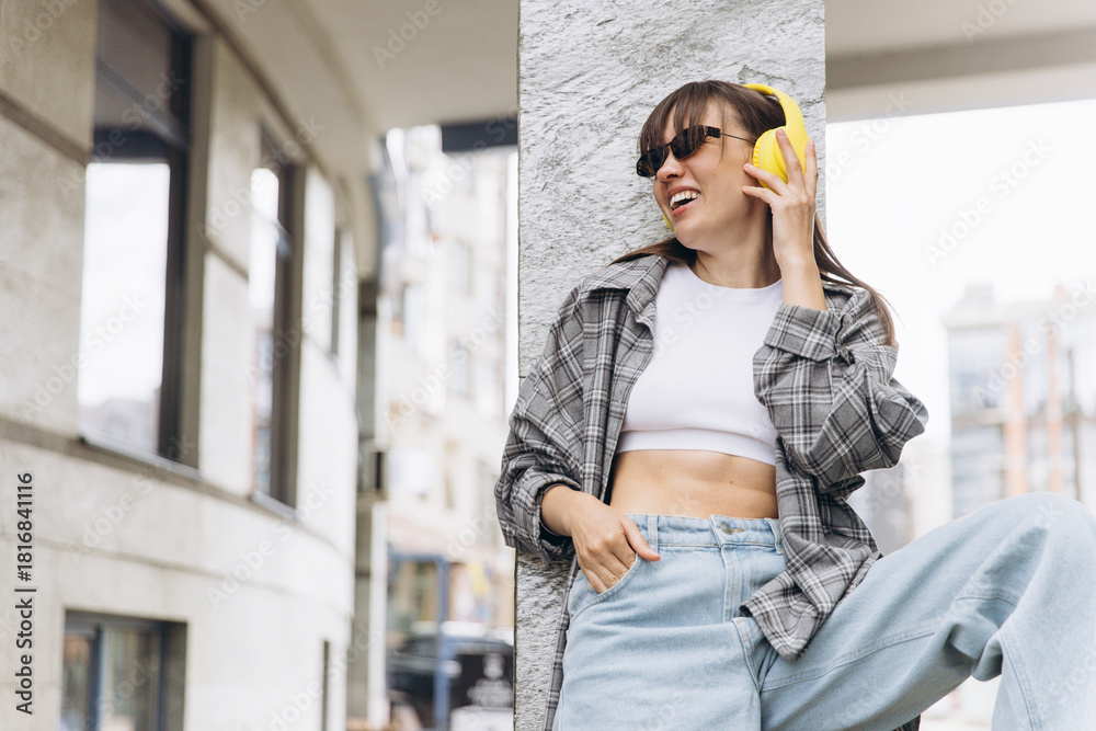 Fototapeta premium Young woman enjoying music with yellow headphones outdoors
