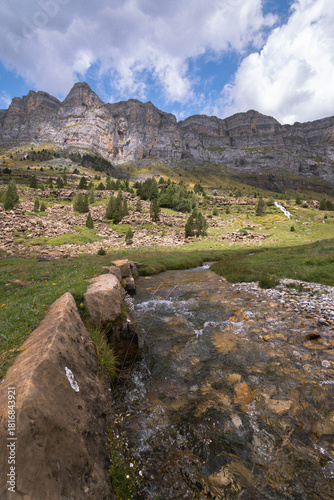 Crystal-Clear Mountain Stream in the Pyrenees with Dramatic Cliffs and Green Valley Landscape