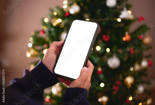 Smartphone screen mockup in hand showcased against festive Christmas lights to emphasize digital holiday marketing mobile app promotion and seasonal online engagement