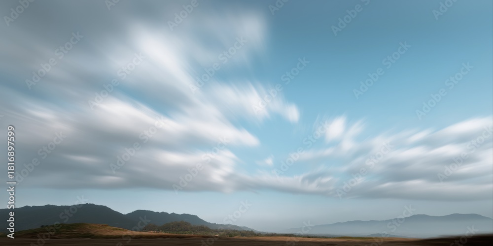 Obraz premium Dynamic clouds over mountainous landscape under blue sky
