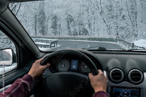 A man drives a car on a winter road in a blizzard