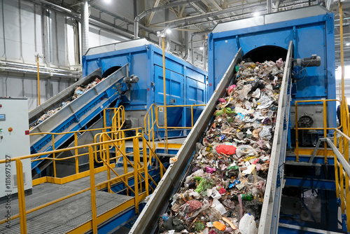 A waste sorting facility operates by separating various types of refuse for recycling. Conveyors carry debris, showcasing an assortment of discarded materials in a clean industrial environment